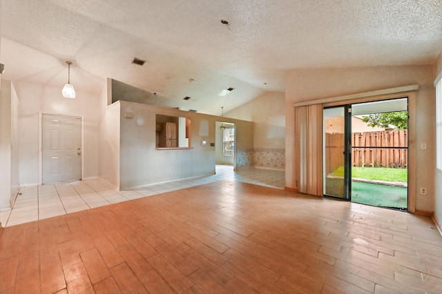 unfurnished living room featuring light hardwood / wood-style floors, a textured ceiling, and vaulted ceiling