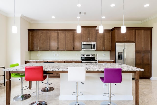 kitchen featuring an island with sink, stainless steel appliances, a kitchen breakfast bar, and light stone countertops