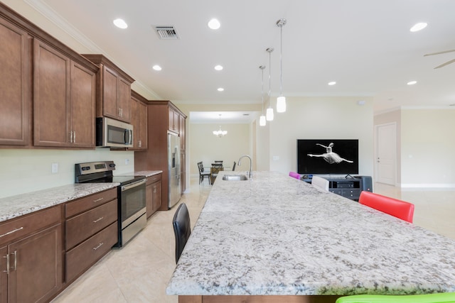 kitchen with light stone counters, stainless steel appliances, and a center island with sink