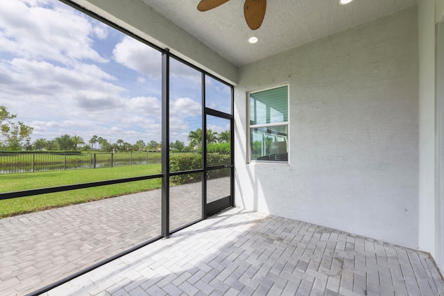 unfurnished sunroom with ceiling fan and a water view