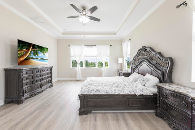 bedroom with light wood-type flooring, a tray ceiling, crown molding, and ceiling fan