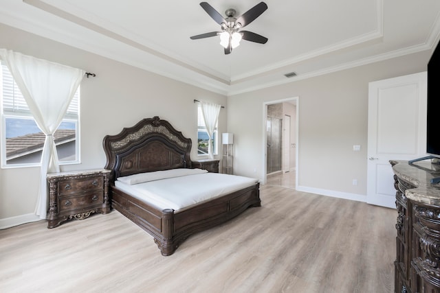 bedroom featuring ensuite bathroom, light hardwood / wood-style floors, a raised ceiling, ceiling fan, and ornamental molding