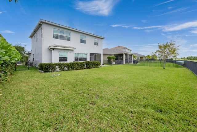 rear view of house featuring a lawn and a sunroom