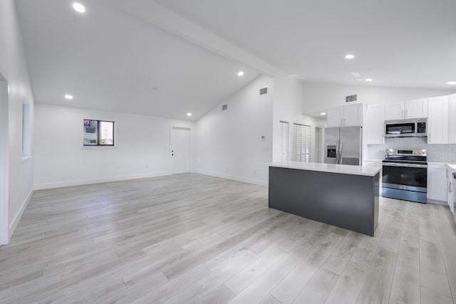 kitchen featuring visible vents, backsplash, appliances with stainless steel finishes, a kitchen island, and beamed ceiling