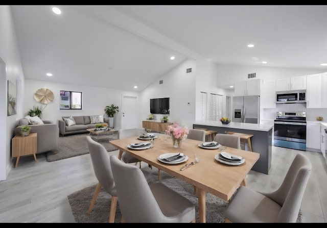 dining area featuring light hardwood / wood-style flooring and vaulted ceiling with beams