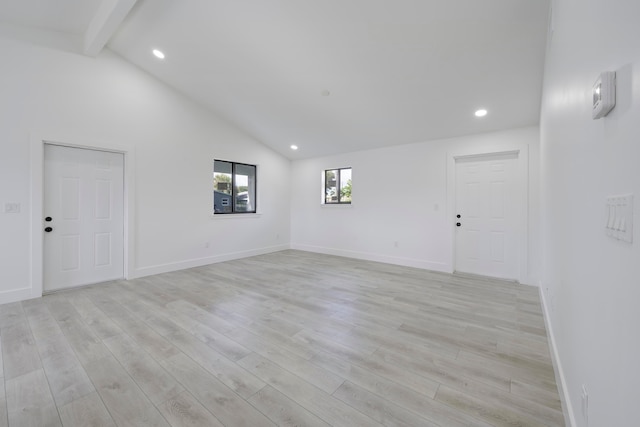 spare room with vaulted ceiling with beams and light hardwood / wood-style flooring