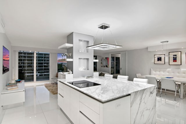 kitchen with black electric stovetop, white cabinetry, decorative light fixtures, a kitchen island, and light tile patterned flooring