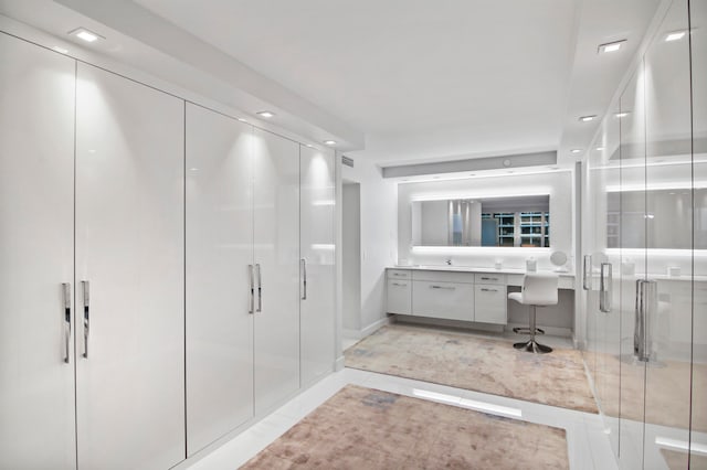 bathroom with a shower with door, vanity, and tile patterned flooring