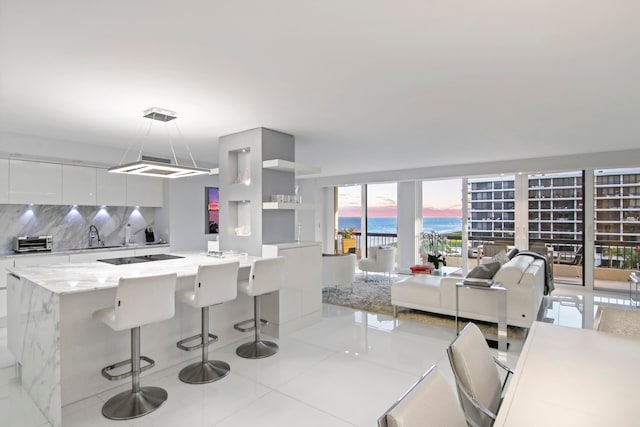 kitchen with a water view, light tile patterned floors, decorative light fixtures, and a wealth of natural light