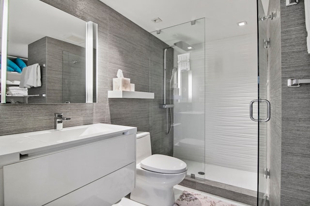 bathroom featuring vanity, toilet, tile walls, and a shower with door