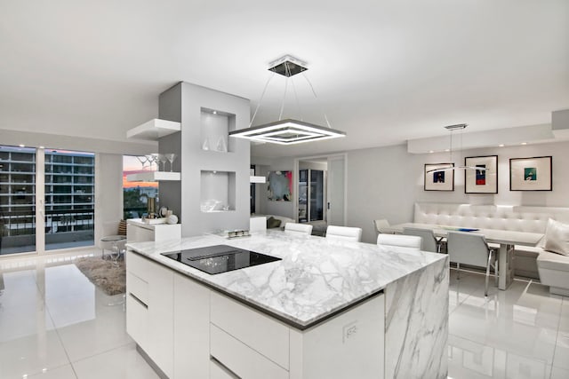 kitchen with white cabinets, light tile patterned floors, black electric cooktop, pendant lighting, and a kitchen island