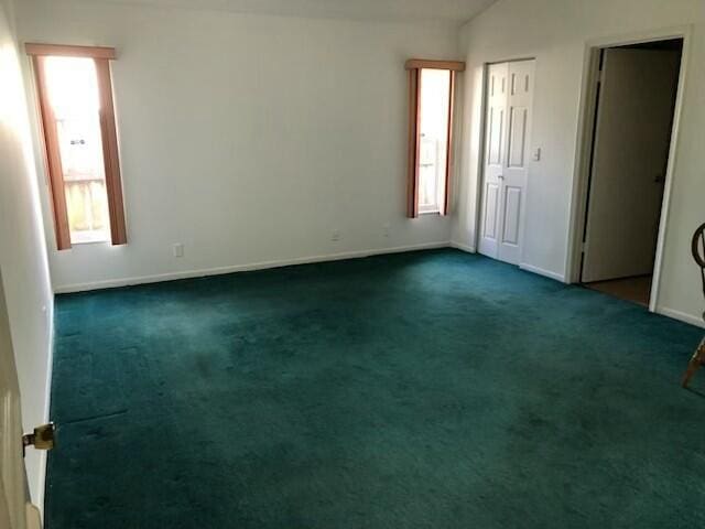 unfurnished room featuring dark carpet and lofted ceiling