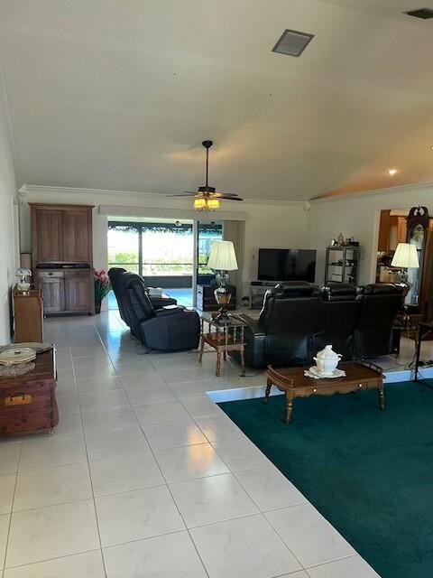 tiled living room featuring ceiling fan and ornamental molding