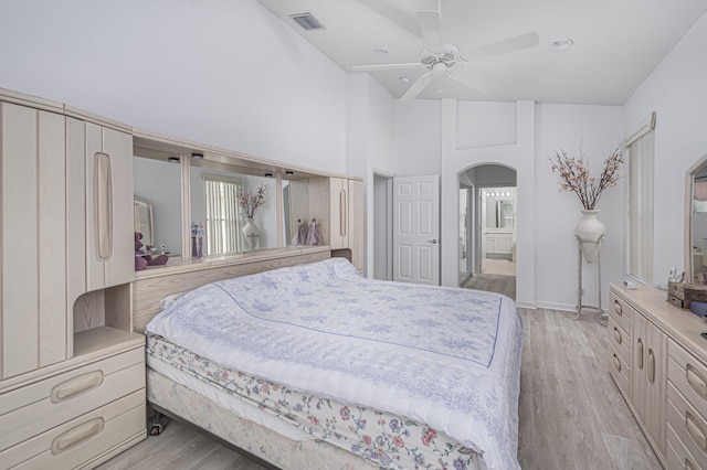 bedroom featuring high vaulted ceiling, ensuite bathroom, ceiling fan, and light hardwood / wood-style floors