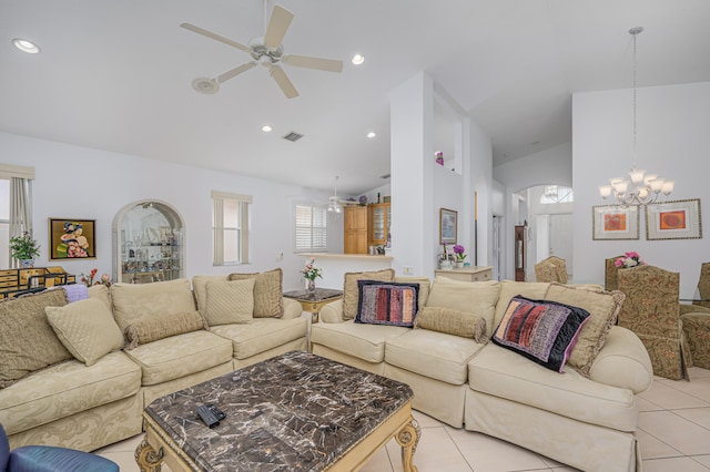 tiled living room featuring ceiling fan with notable chandelier and high vaulted ceiling