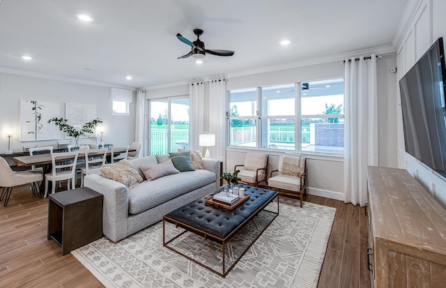 living room featuring ceiling fan, wood-type flooring, crown molding, and a healthy amount of sunlight