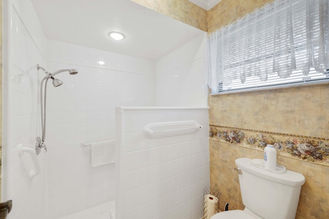 bathroom with tiled shower, toilet, and tile walls