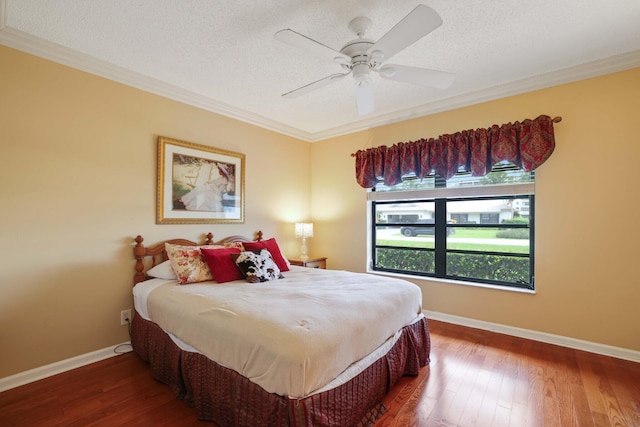 bedroom featuring crown molding, dark wood-type flooring, a textured ceiling, and ceiling fan