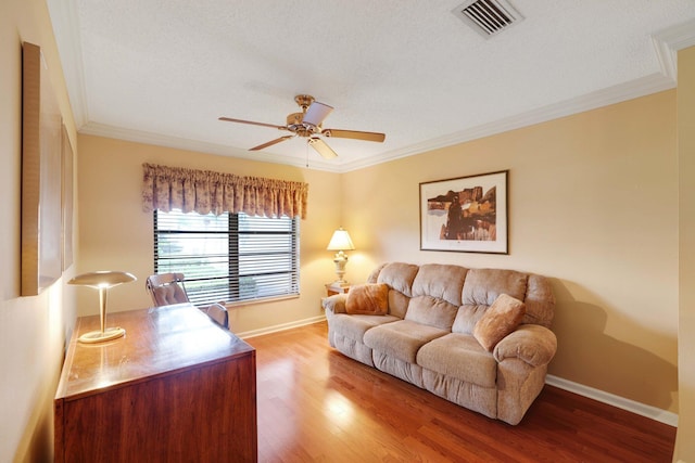 living room featuring hardwood / wood-style floors, ceiling fan, crown molding, and a textured ceiling