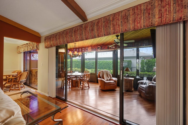 living room with hardwood / wood-style flooring, a textured ceiling, vaulted ceiling, ceiling fan with notable chandelier, and ornamental molding