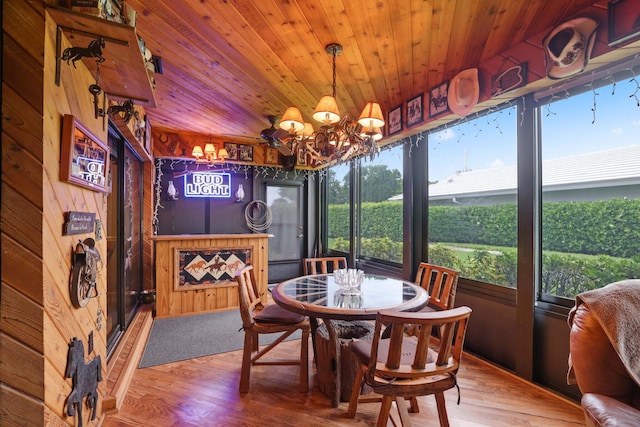 dining area featuring wooden ceiling, wood walls, wood-type flooring, and an inviting chandelier