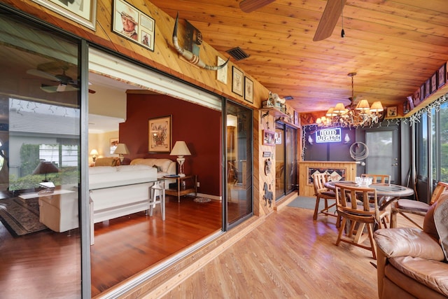 dining room featuring hardwood / wood-style floors, wooden walls, ceiling fan with notable chandelier, wooden ceiling, and lofted ceiling