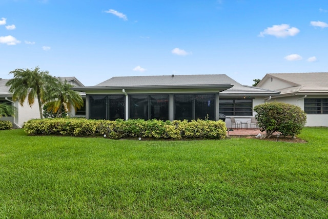 rear view of property featuring a sunroom and a yard