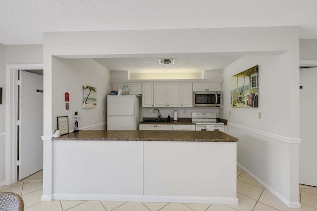 kitchen with sink, light tile patterned floors, white appliances, and white cabinets