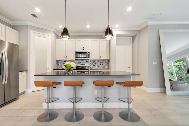 kitchen featuring white cabinets, appliances with stainless steel finishes, a kitchen breakfast bar, and a center island with sink