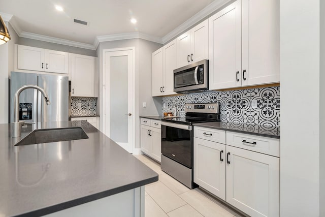 kitchen featuring appliances with stainless steel finishes, backsplash, sink, and white cabinets