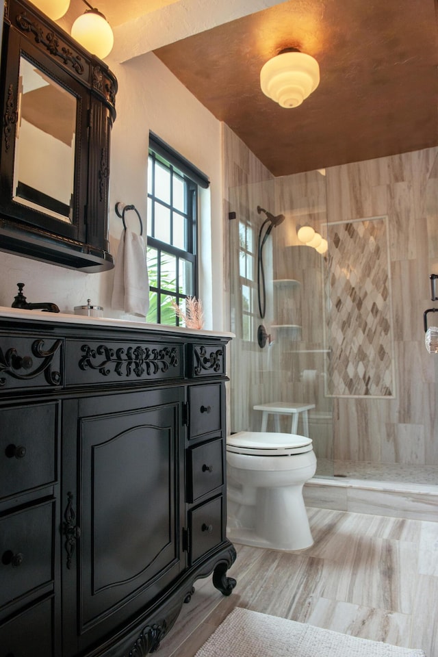 bathroom with vanity, toilet, and tiled shower