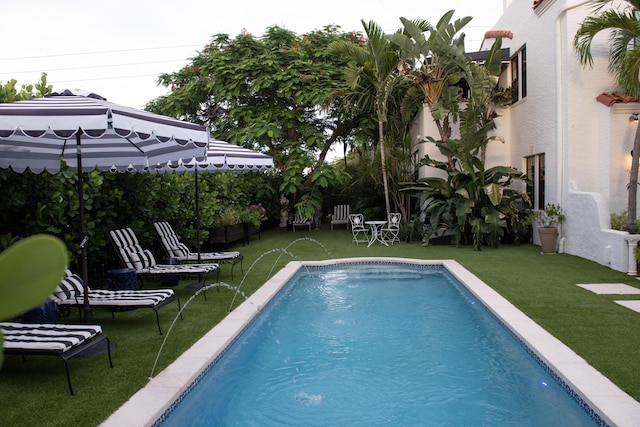 outdoor pool featuring a lawn and a patio area