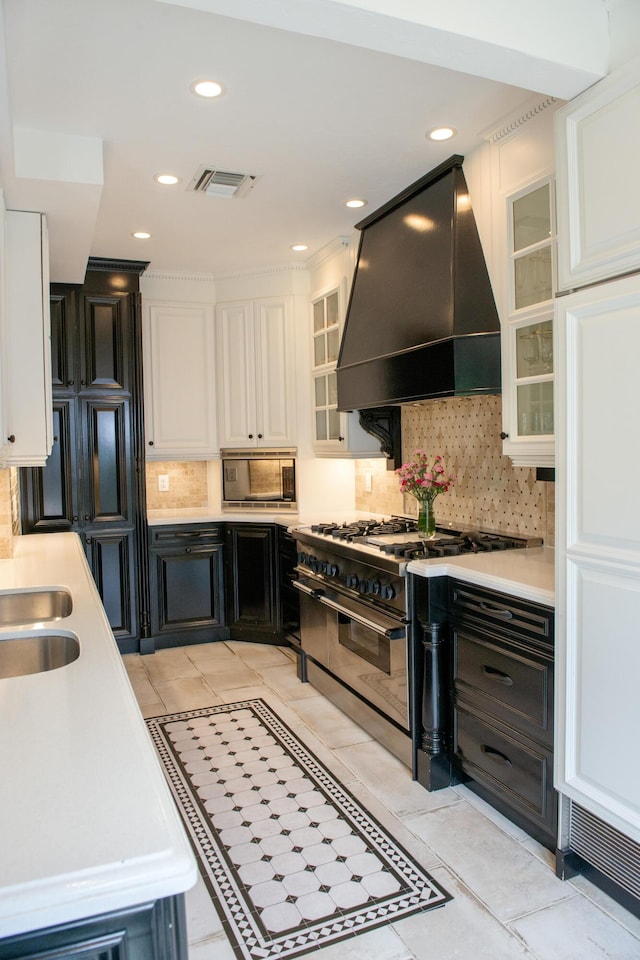 kitchen with stainless steel range, custom exhaust hood, light countertops, visible vents, and black microwave