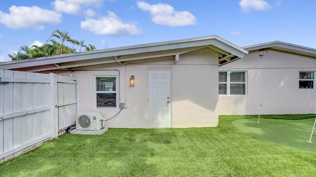 2600 NE 30th St, Fort Lauderdale, FL 33306 - back of property with ac unit, stucco siding, fence, and a lawn