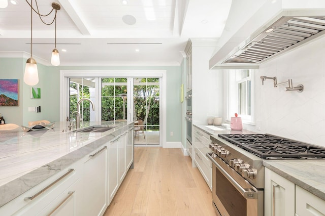 kitchen featuring light stone counters, exhaust hood, high end range, and sink