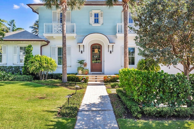 view of front of house with a balcony and a front lawn