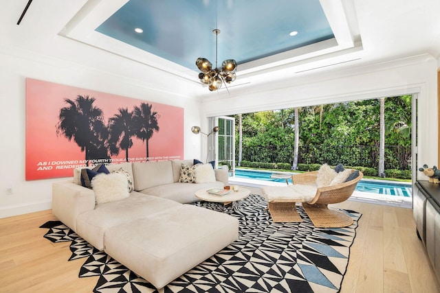 living room featuring light wood-type flooring, a raised ceiling, crown molding, and a wealth of natural light