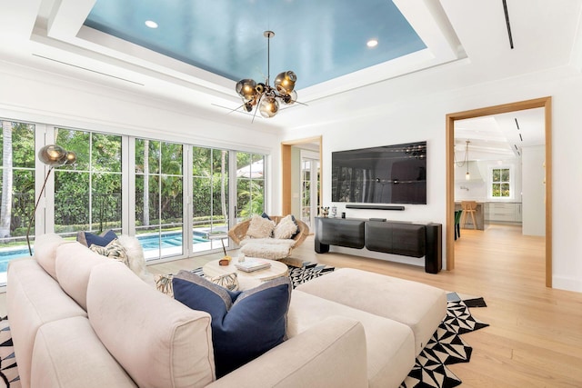 living room with a tray ceiling, light wood-type flooring, and a wealth of natural light