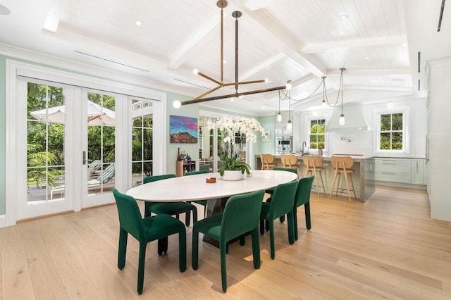 dining room with a notable chandelier, light hardwood / wood-style floors, lofted ceiling with beams, and sink