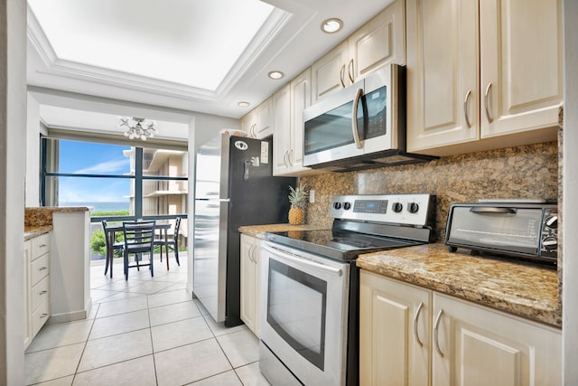 kitchen featuring light stone counters, a chandelier, light tile patterned floors, a wall of windows, and appliances with stainless steel finishes