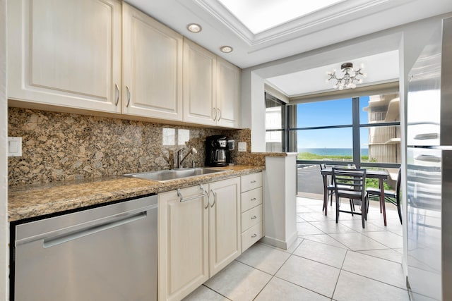 kitchen with appliances with stainless steel finishes, ornamental molding, light tile patterned floors, a raised ceiling, and a notable chandelier