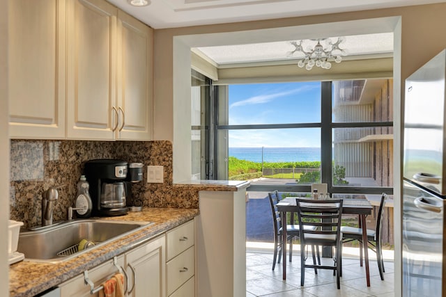 kitchen featuring tasteful backsplash, light stone counters, light tile patterned flooring, sink, and dishwasher