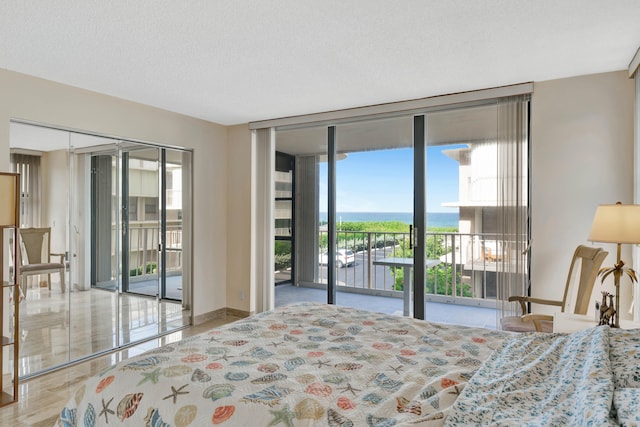 tiled bedroom featuring access to outside, a water view, a textured ceiling, floor to ceiling windows, and a closet