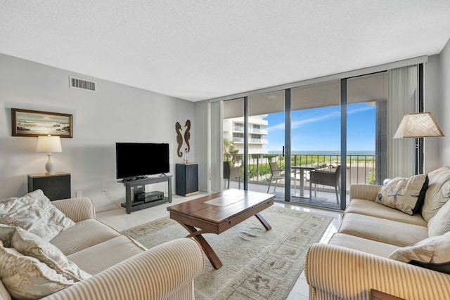 tiled living room featuring a textured ceiling, a healthy amount of sunlight, and floor to ceiling windows