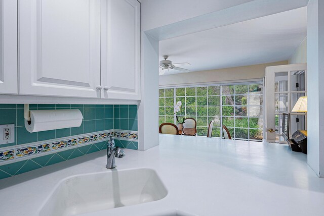 kitchen featuring ceiling fan, sink, and white cabinetry