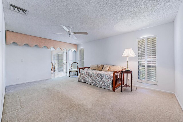 bedroom with a textured ceiling, ceiling fan, and light carpet