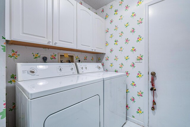 laundry room with washer and dryer, cabinets, and a textured ceiling