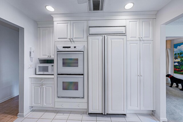 kitchen with light colored carpet, white appliances, and white cabinets