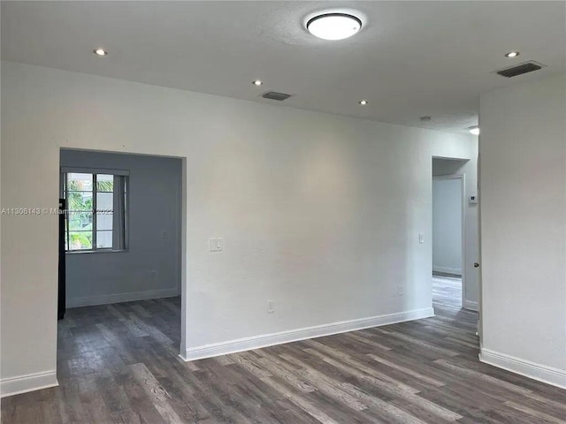 spare room with visible vents, dark wood finished floors, and baseboards