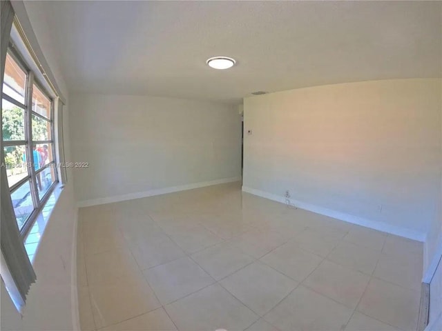 spare room with light tile patterned floors, visible vents, and baseboards